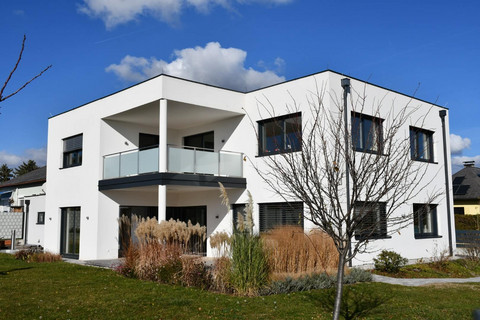 Modernes Ziegelmassivhaus von Binder Bau - energieeffizientes Einfamilienhaus in klarer Architektursprache mit Flachdach, großzügiger Terrasse und durchdachtem Beschattungskonzept durch horizontale Lamellen