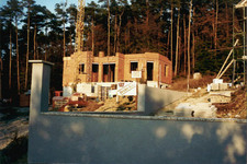 Historische Baustelle von Binder Bau im Waldgebiet - Rohbau eines Ziegelhauses mit Baukran und Binder Bau Baustellenschild